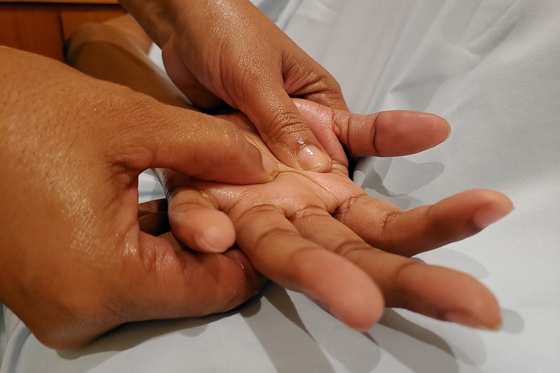 A spa guest receives a hand massage from a massage therapist.