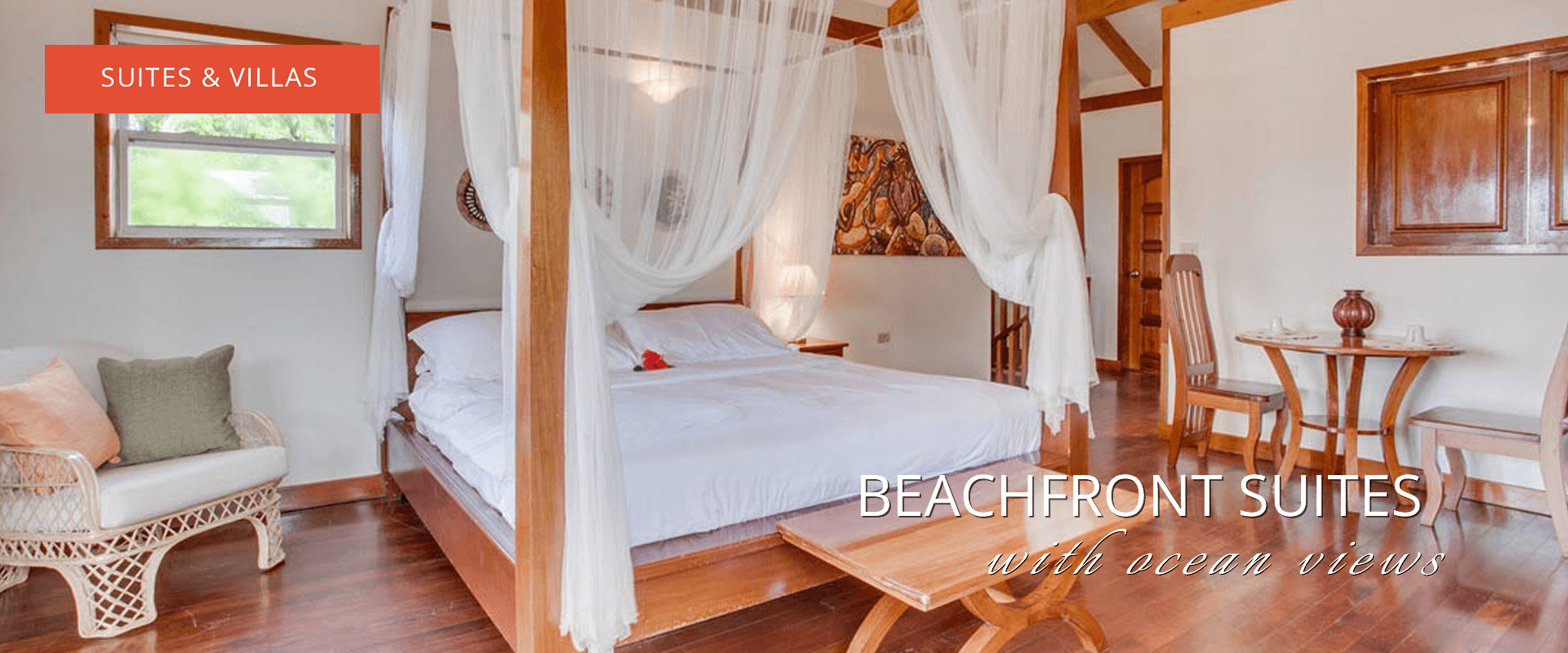 Four poster bed with white coverlet.  Wooden furniture and tiled floors.  Text says "Suite & Villas" and "Beachfront suites with ocean views"