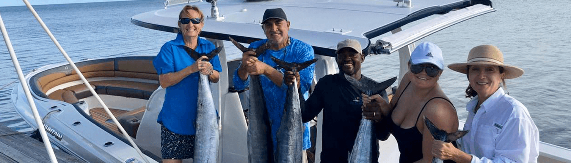 A group of people in a fishing boat proudly hold up their catch of deep-sea fish.