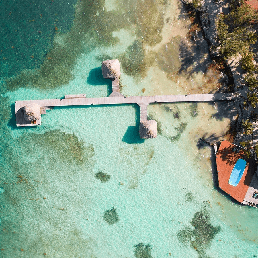 Ariel view of dock out to 3 huts in the water, and pool on the island.