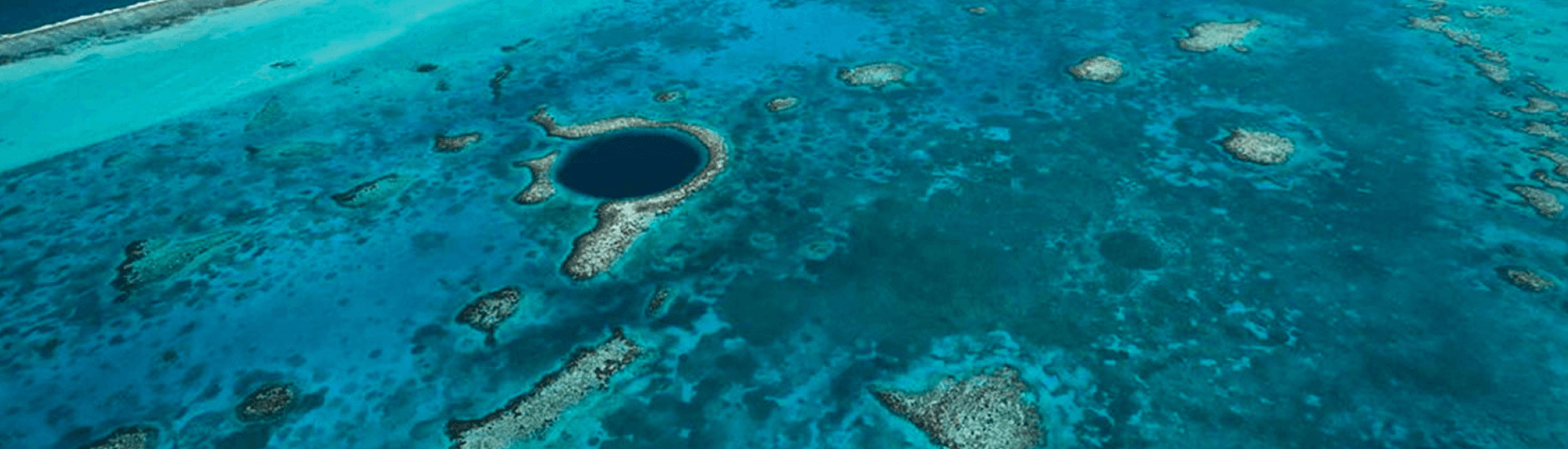 A breathtaking aerial view of the Great Blue Hole, a circular abyss surrounded by vibrant coral reefs in the Caribbean Sea.